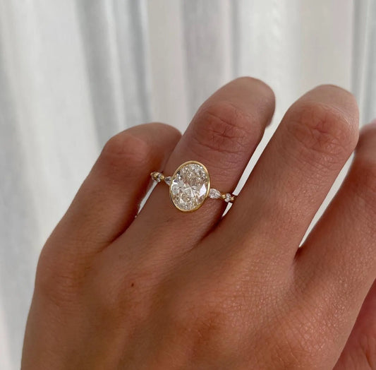 Gold ring with a large diamond on a person's finger against a white background