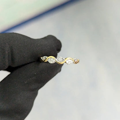 Gold ring with three diamonds held by a black-gloved hand on a light gray background