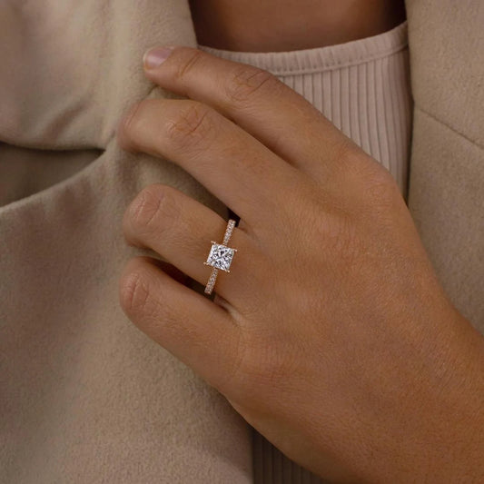 Close-up of a hand wearing a diamond ring with a neutral background
